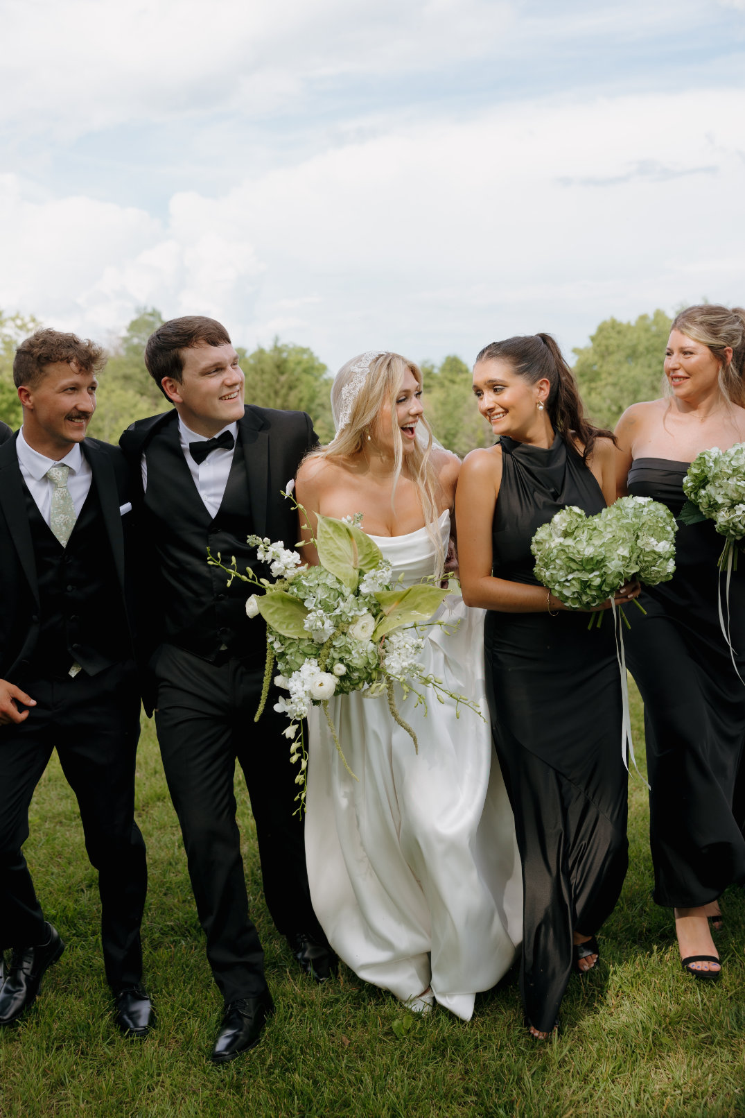 Wedding party walking together outdoors at The Seventy Five Venue in Hocking Hills, Ohio, captured in a candid, modern style by Chloe Elizabeth Photography.