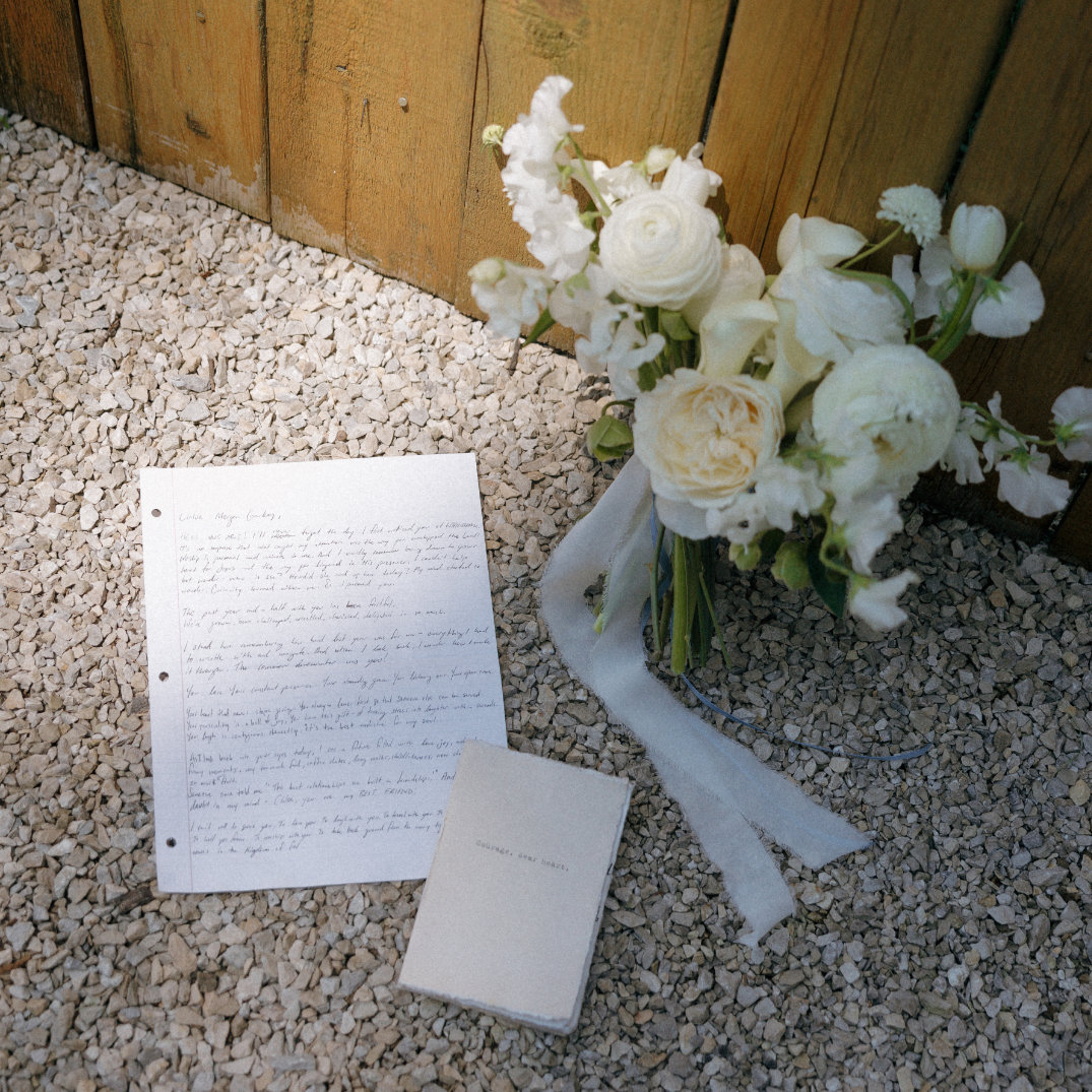 Flat lay of wedding stationery and bouquet styled on stone steps.