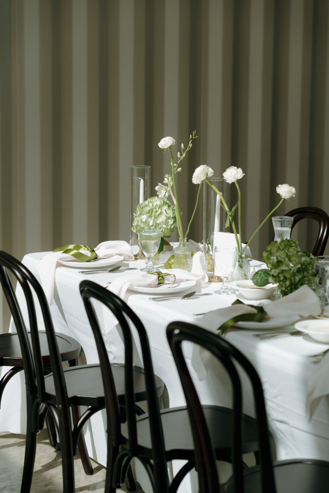 Minimalist reception table styling with candles, glassware, and delicate floral arrangements.