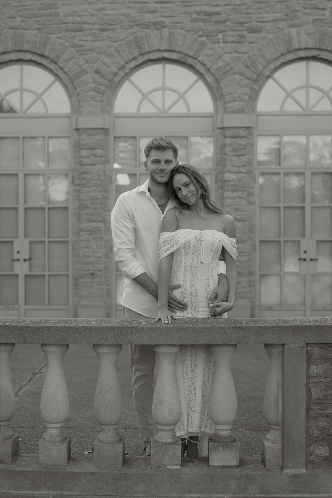 Black and white portrait of the couple posing together in front of a decorative stone wall, captured by Ohio film photographer