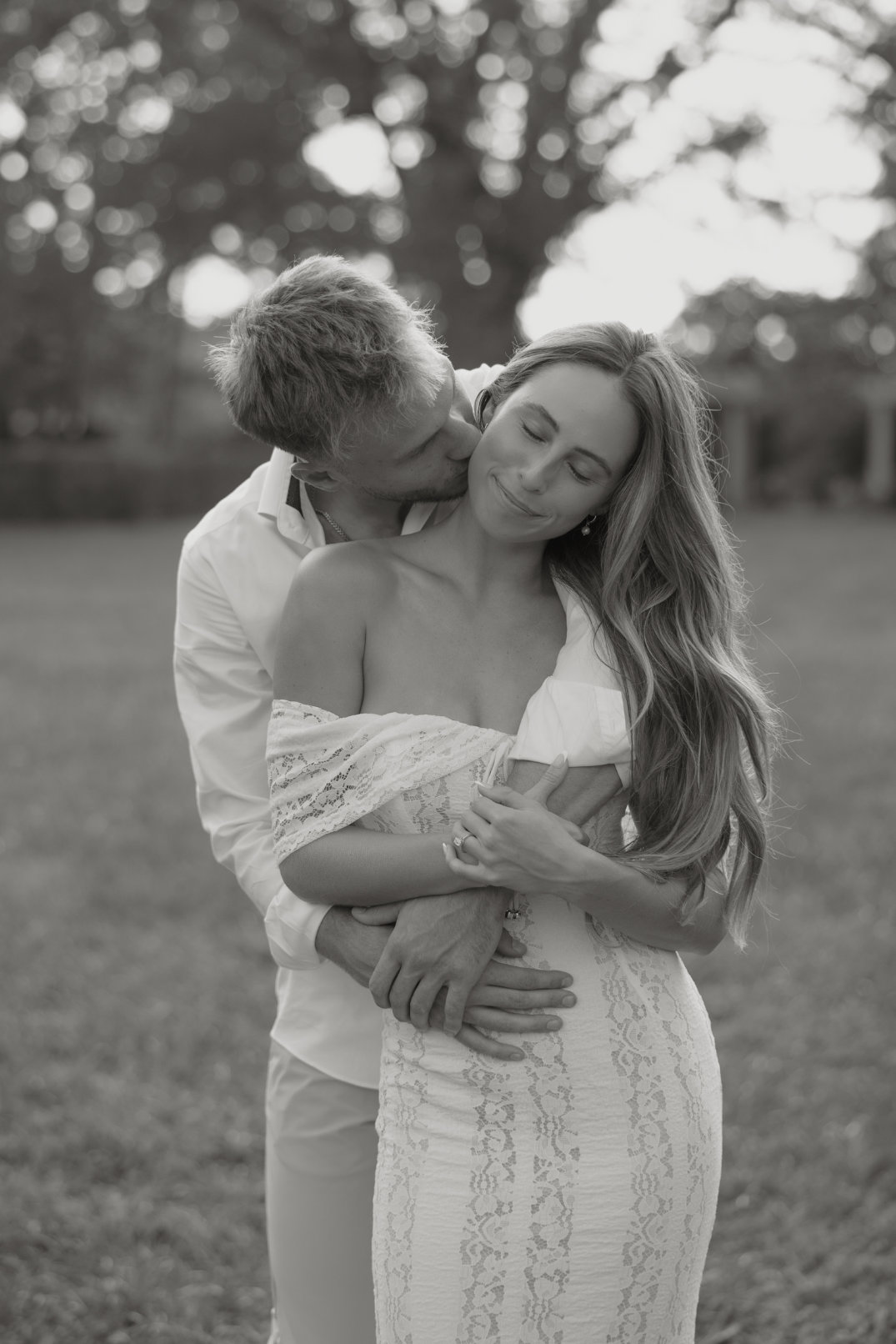 Black and white image of the couple embracing closely while standing together.