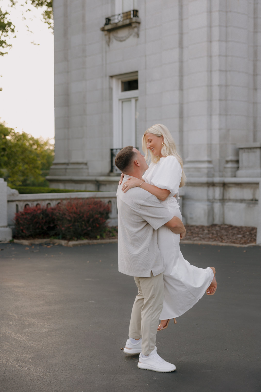 The groom lifting the bride slightly off the ground as they laugh together.