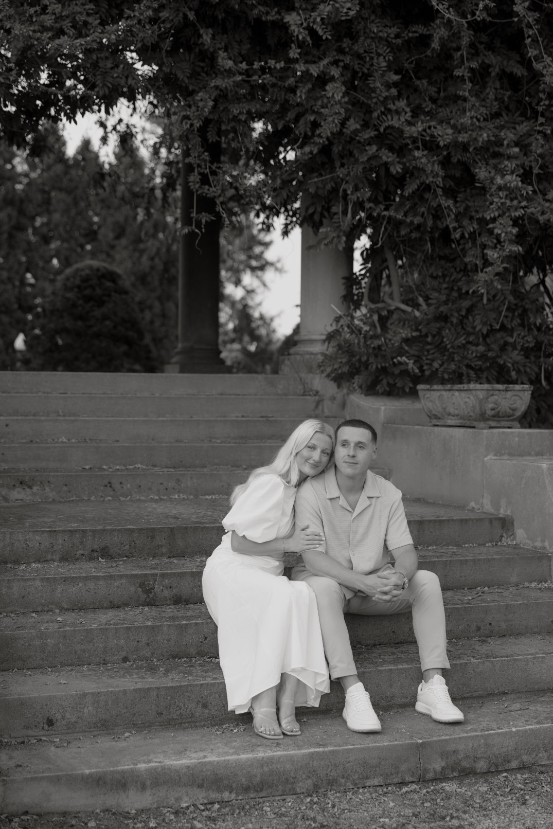 Black and white image of the couple sitting closely together on steps, sharing a quiet moment.