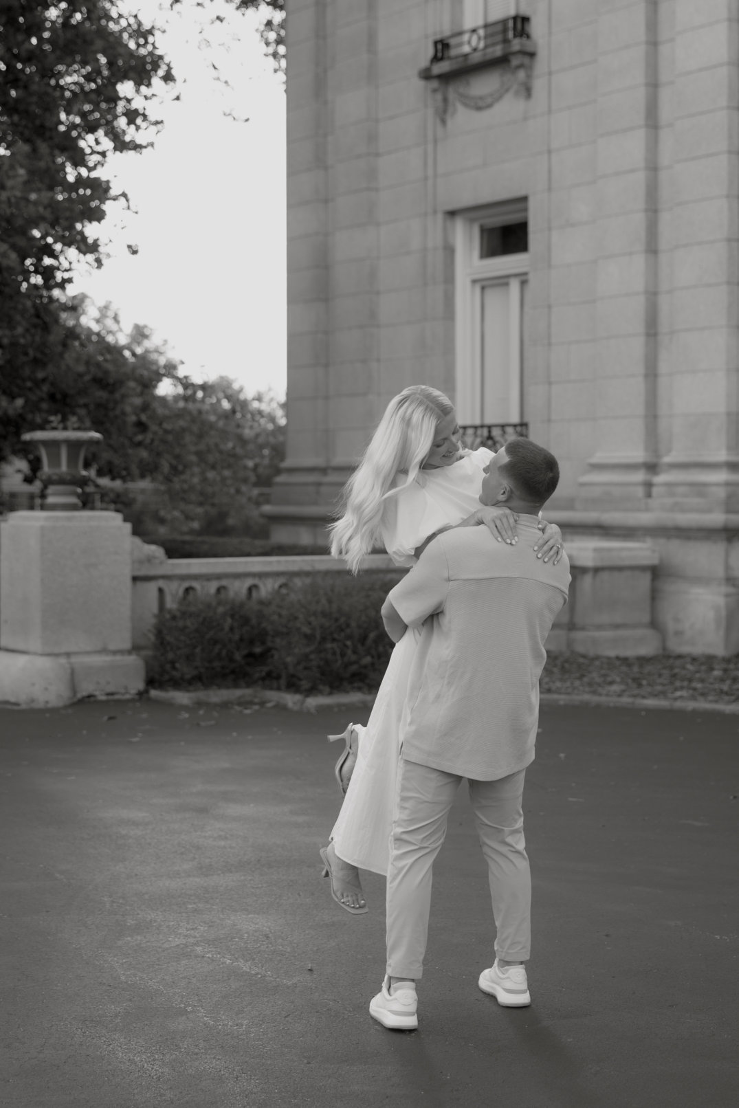 Black and white photo of the couple spinning playfully in an open courtyard.
