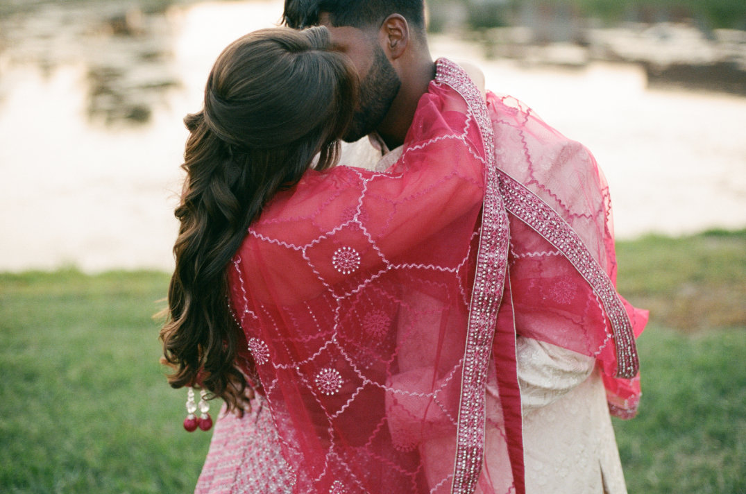 Couple embracing outdoors during a cultural celebration, dressed in vibrant formalwear.