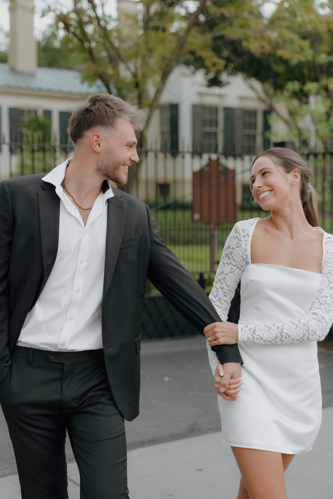 The couple walking hand in hand across a paved area in formal attire during golden hour in Cincinnati, Ohio.