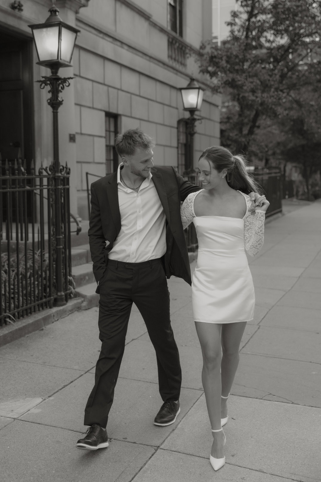 Black and white photo of the couple dancing or celebrating together near an ornate building