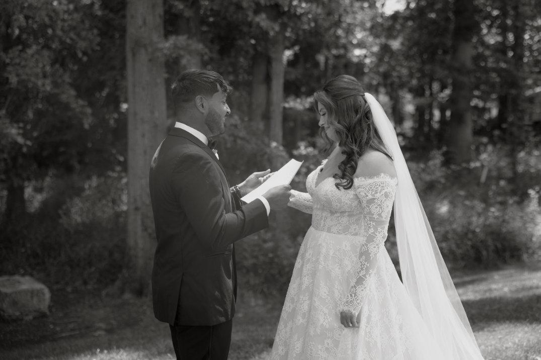 Black and white photo of the couple holding hands during the ceremony, captured with a soft, romantic feel.