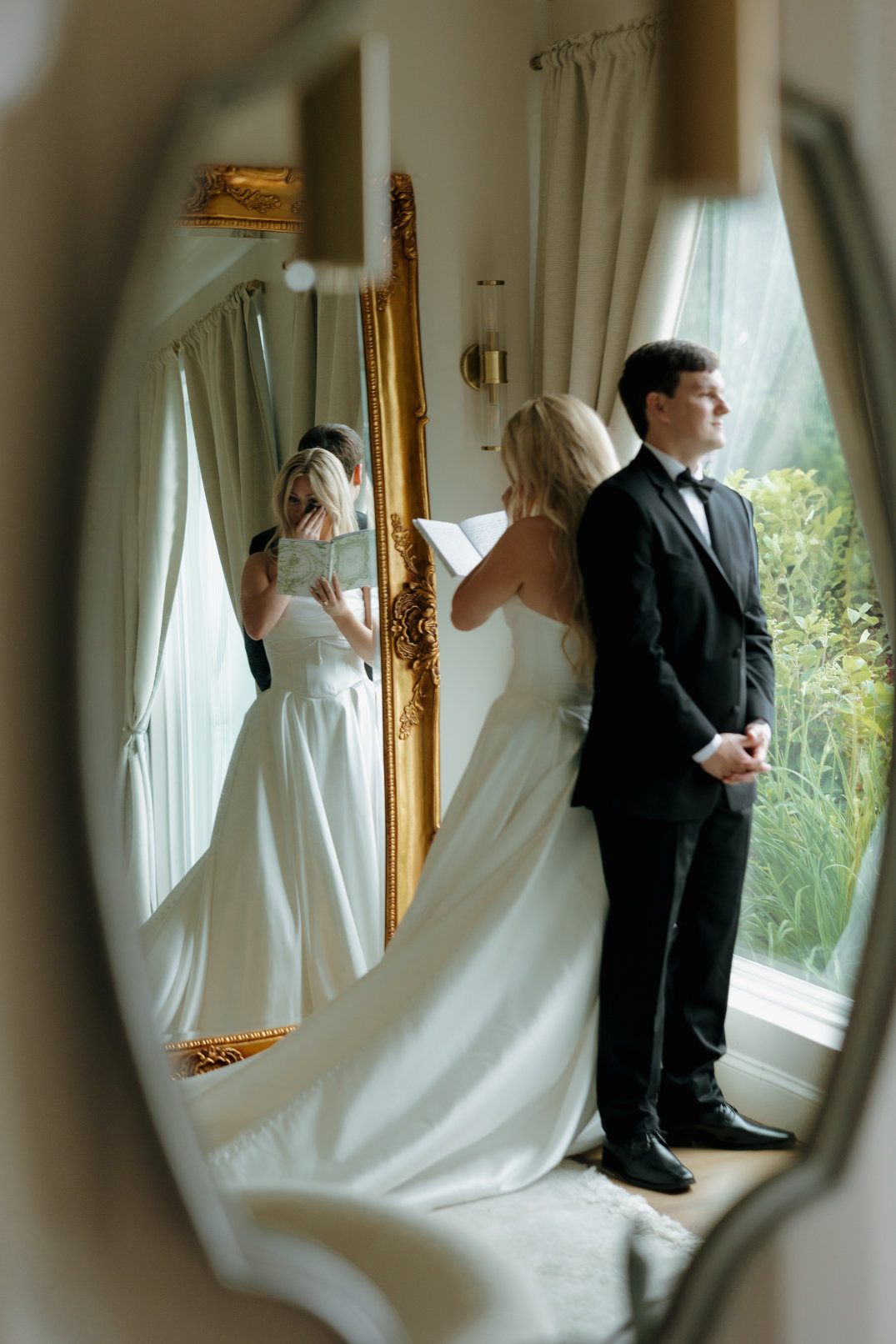 Ohio Bride and groom stand back-to-back by a window, reflected in a mirror. She reads a letter, creating a touching and intimate wedding moment.