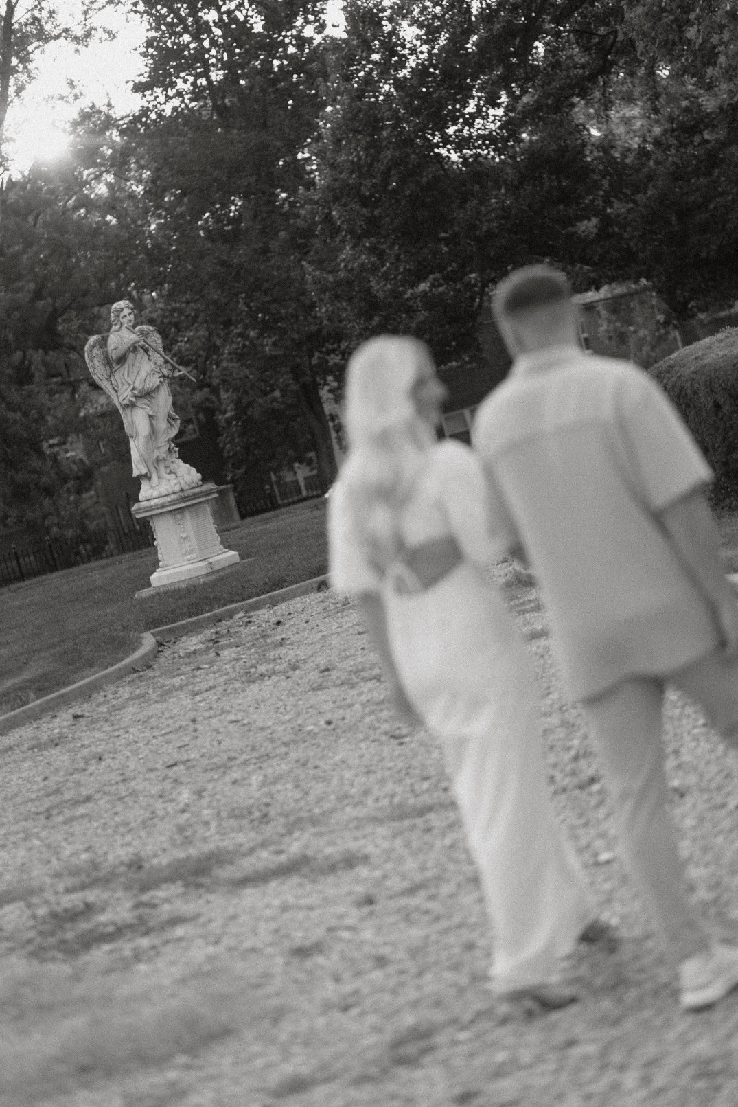 Black and white image of the couple walking away together across the lawn.