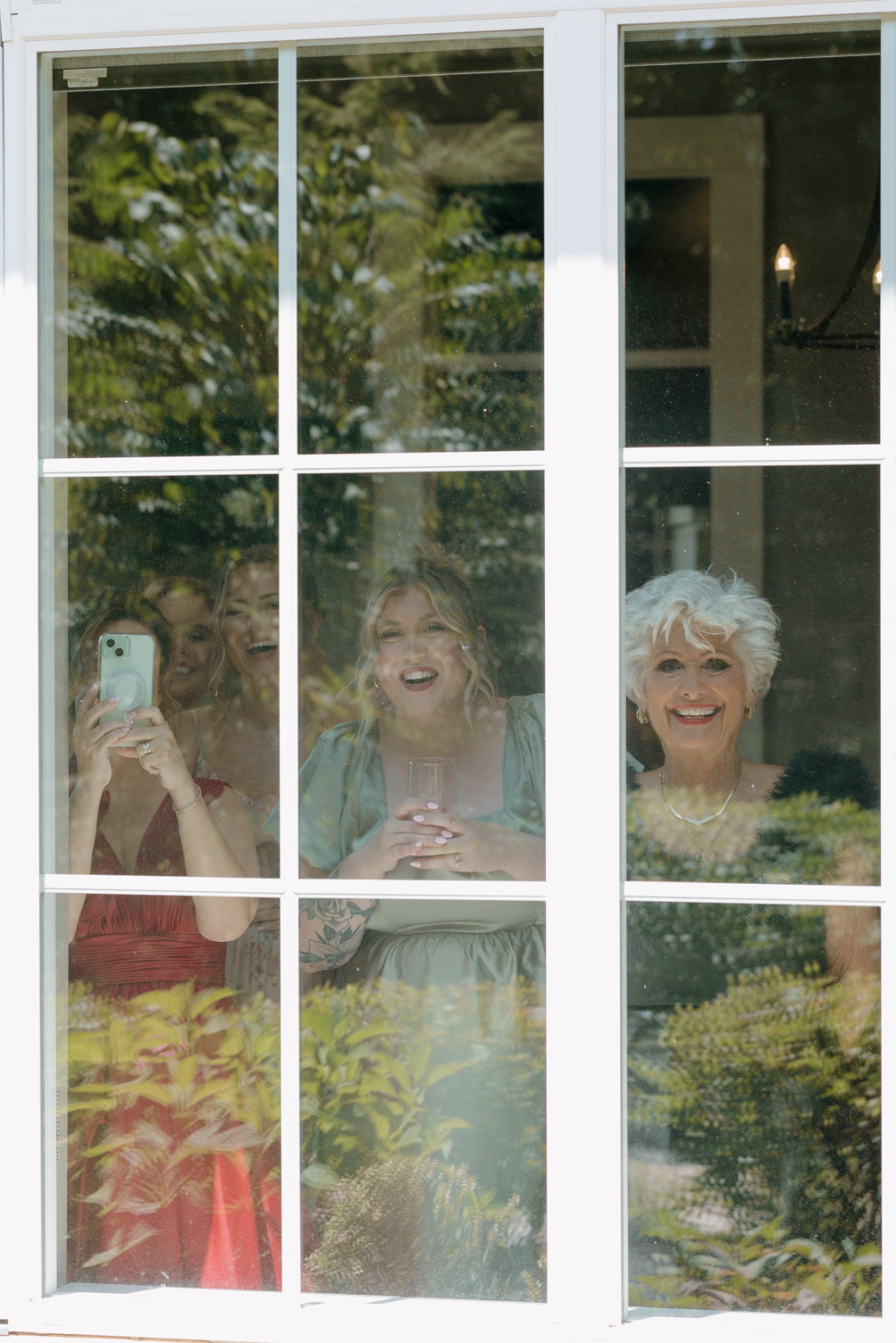 Guests smiling and watching through a window during the first look.