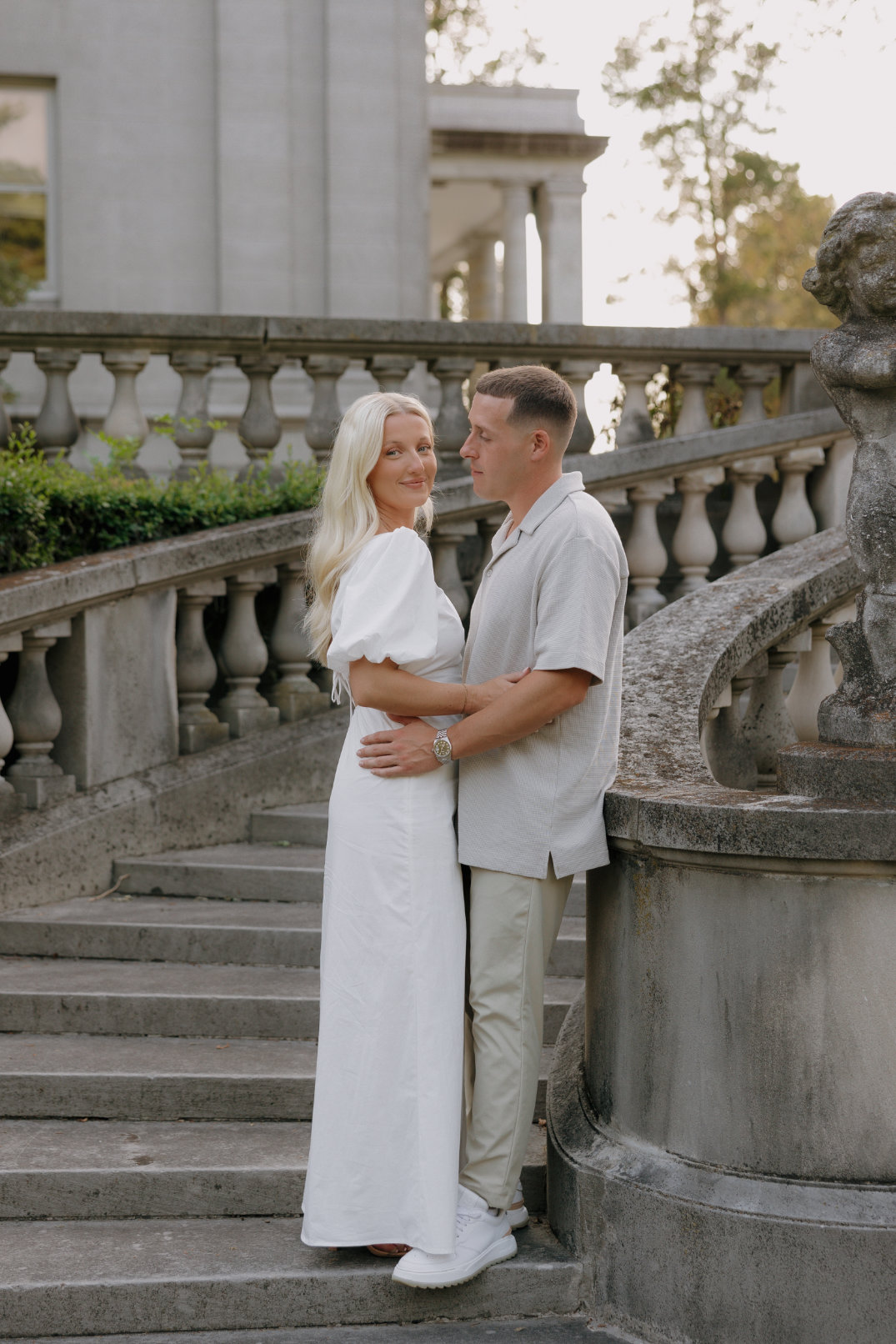 Couple standing together on curved stone steps, embracing softly during an engagement session at Laurel Court, Cincinnati.