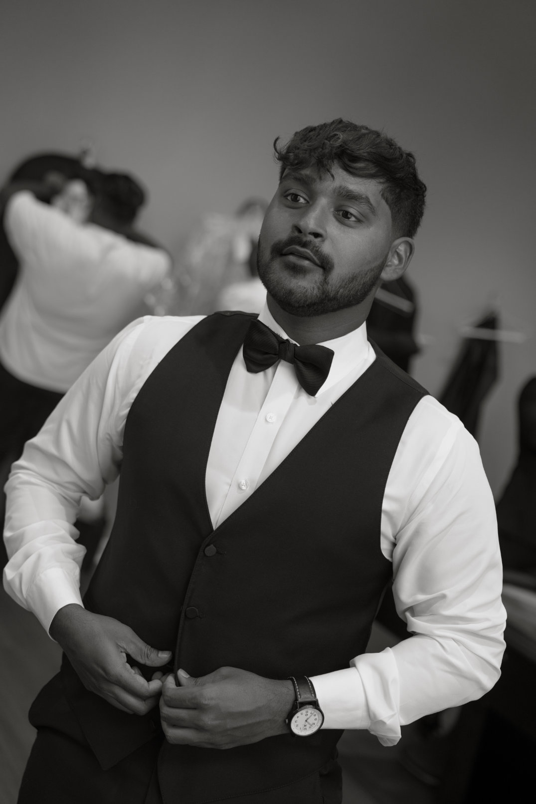 Black and white portrait of the groom adjusting his vest while getting ready, captured by film photographer Ohio.