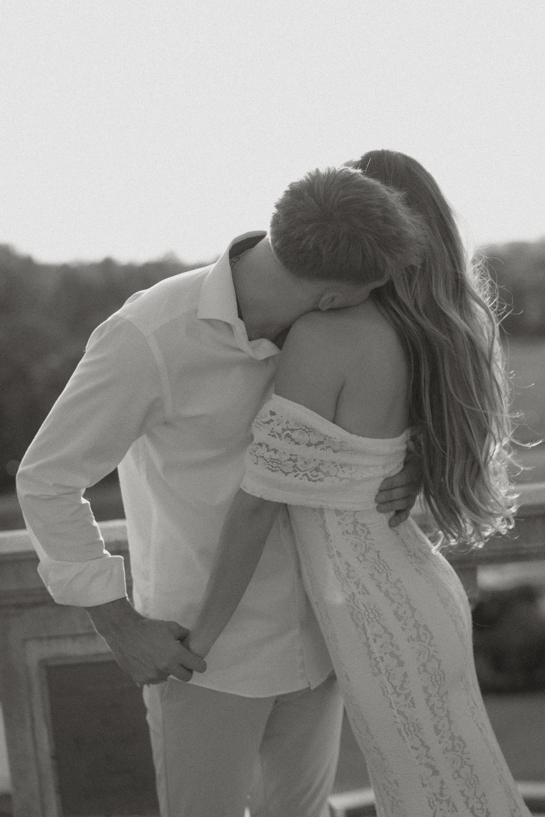 Black and white image of the couple kissing, photographed from behind.