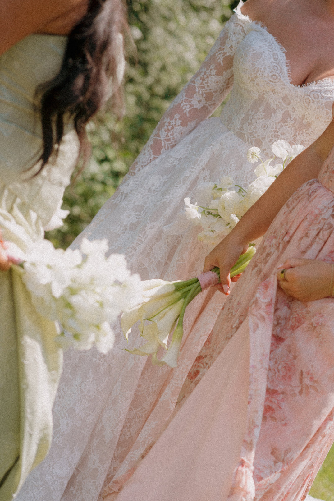 Close-up detail of bridesmaids’ dresses and bouquets as they walk together.