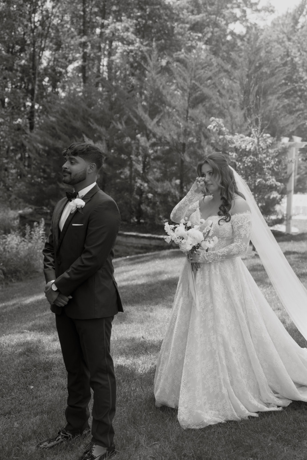 Black and white photo of the couple standing together during their first look.