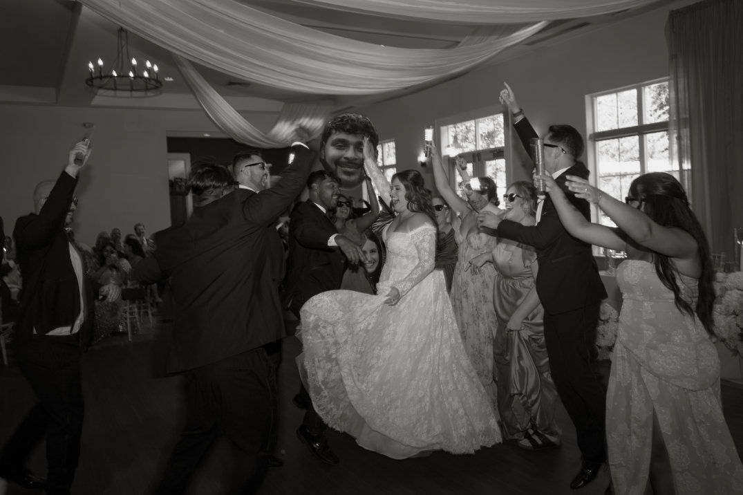 Black and white photo of the couple dancing together during the reception, surrounded by guests.