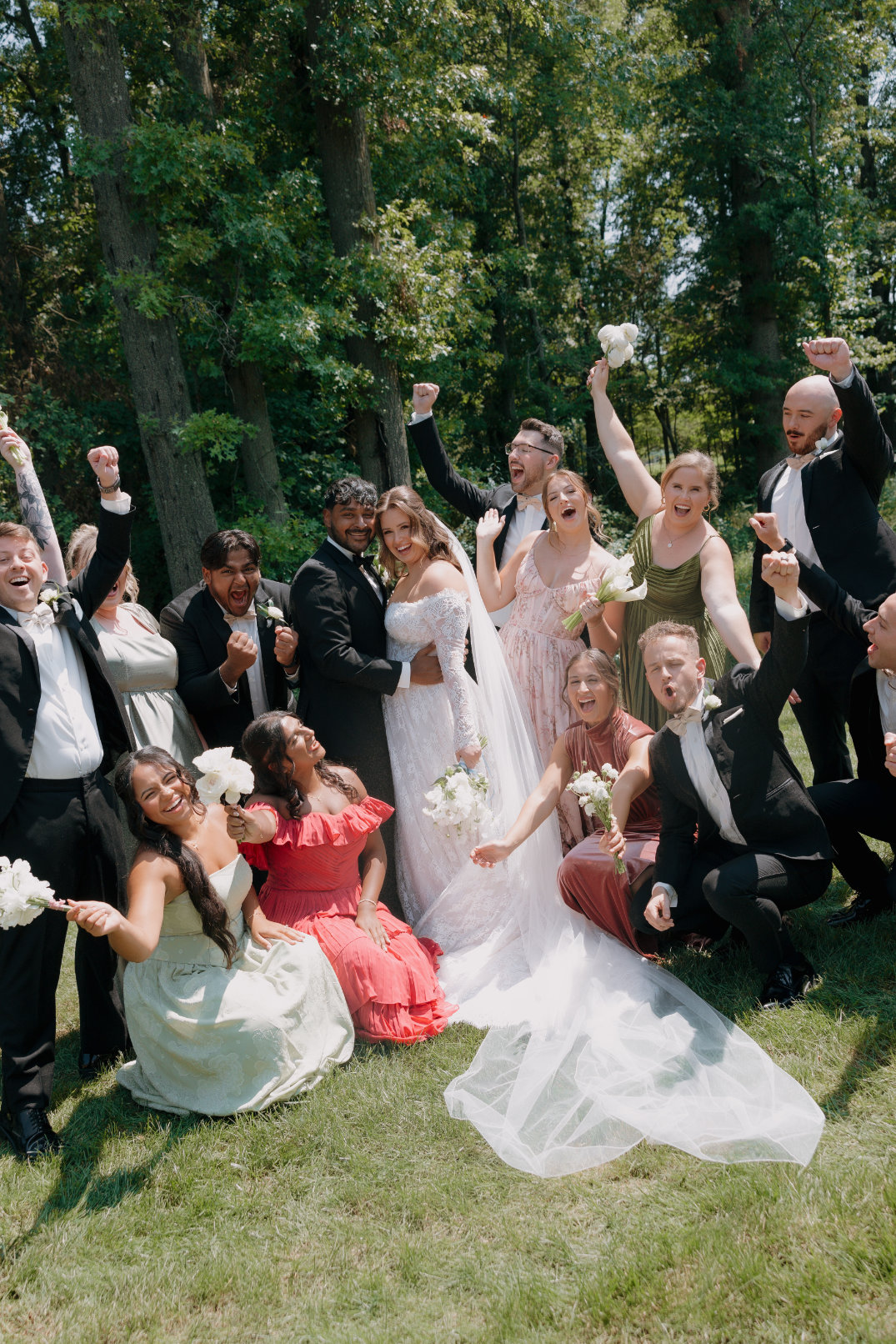 Large group photo with the couple seated and guests cheering around them after the ceremony.