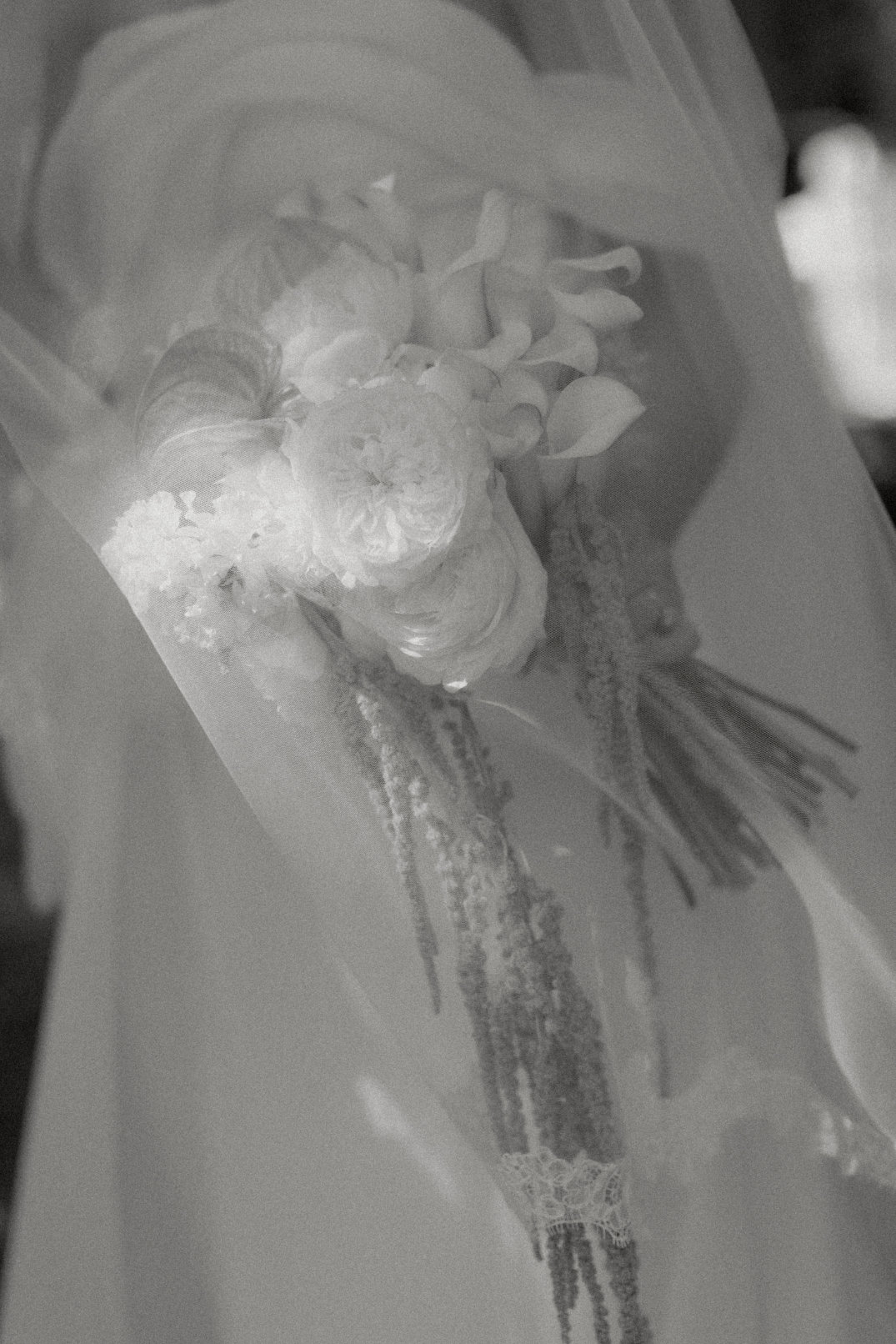 Black and white film photo of an Ohio bride holding a bouquet of roses and calla lilies. Veil softly drapes over the flowers, creating an elegant and serene mood.